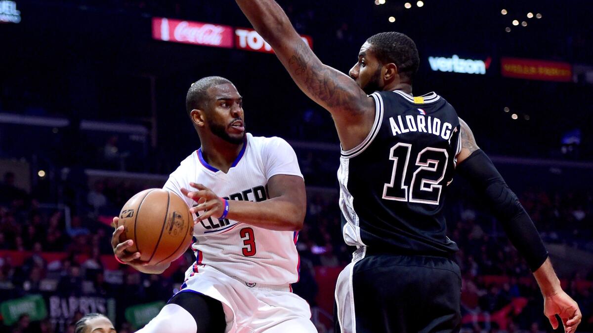 Clippers point guard Chris Paul looks to pass after driving to the basket against Spurs forward LaMarcus Aldridge during the first half Friday night.
