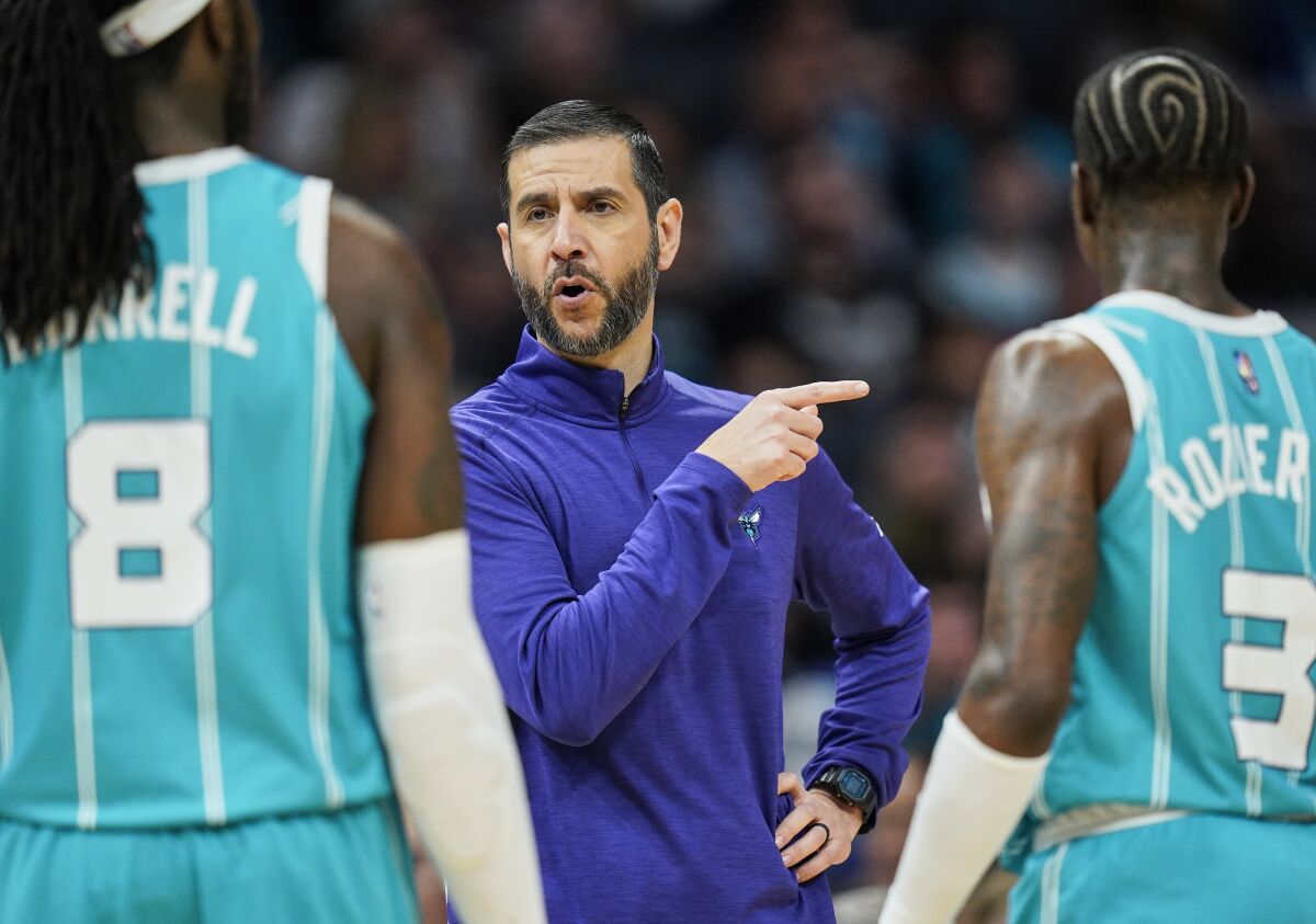 Charlotte Hornets head coach James Borrego, center, gives instruction to Charlotte Hornets center Montrezl Harrell (8) and guard Terry Rozier (3) during the first half of an NBA basketball game against the Orlando Magic on Thursday, April 7, 2022, in Charlotte, N.C. (AP Photo/Rusty Jones)