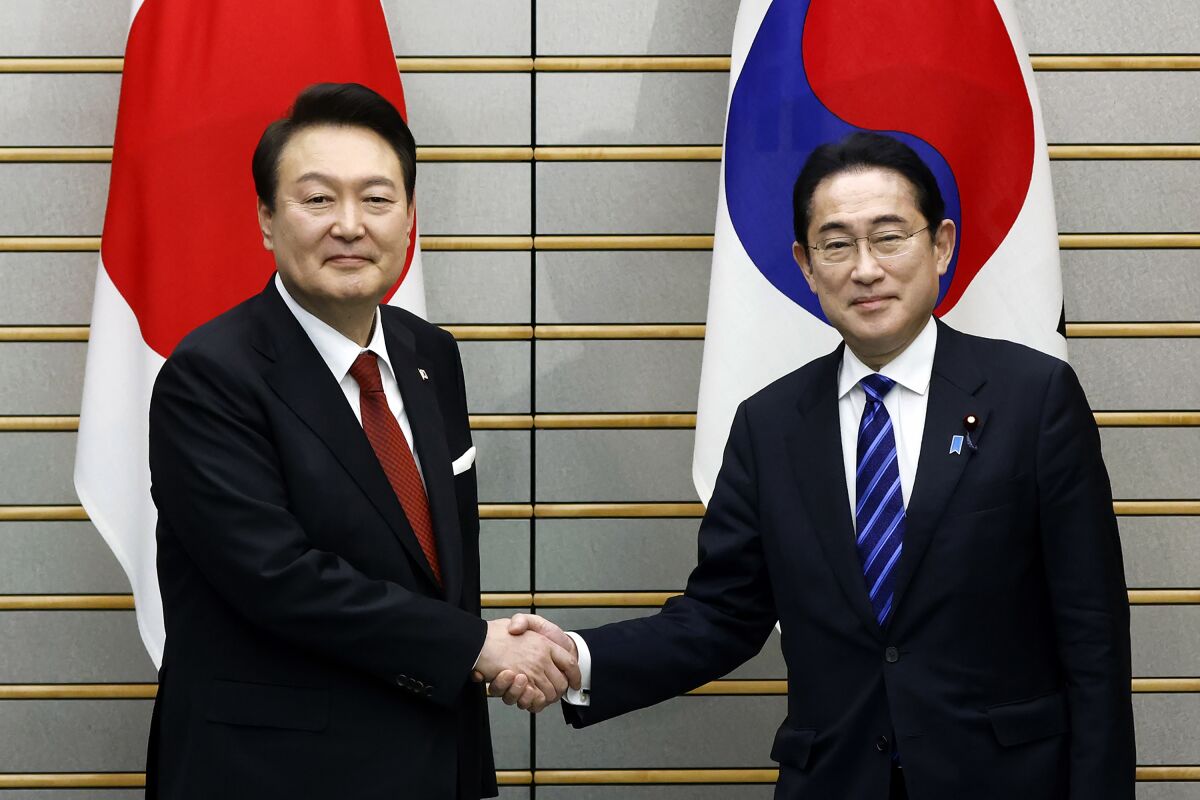 South Korean President Yoon Suk Yeol, left, and Japanese Prime Minister Fumio Kishida, right, shake hands, ahead of their bilateral meeting at the Prime Minister's Office, in Tokyo, Japan, Thursday, March 16, 2023. (Kiyoshi Ota/Pool Photo via AP)