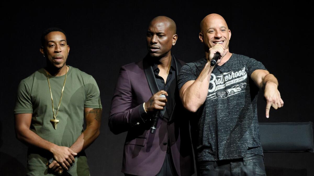 Chris Bridges, left, Tyrese Gibson, and Vin Diesel, cast members in the upcoming film "The Fate of the Furious," interact with the audience during the Universal Pictures presentation at CinemaCon 2017.