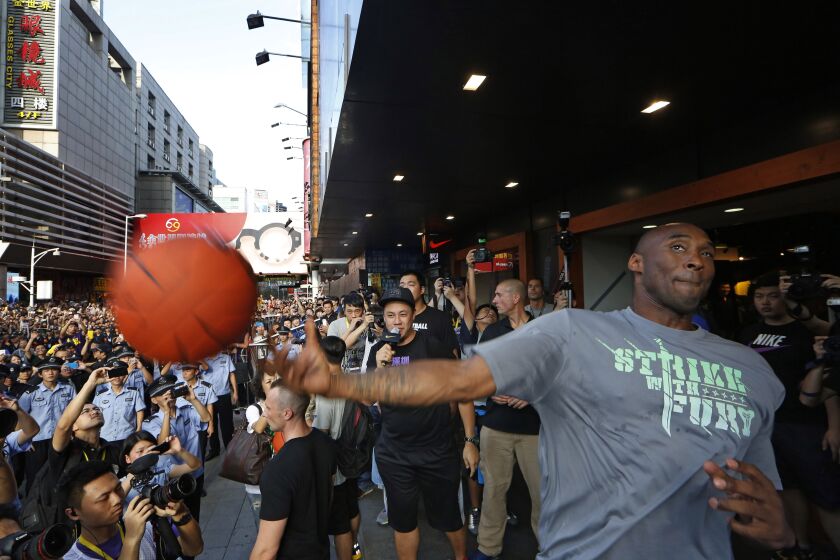 Kobe Bryant throws a ball to his fans during a promotional event in Shenzhen, China, Aug. 4, 2013.