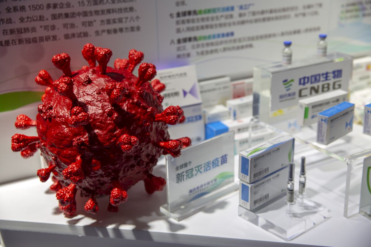 A model of a coronavirus is displayed next to boxes for COVID-19 vaccines at an exhibit by Chinese pharmaceutical firm Sinopharm at the China International Fair for Trade in Services (CIFTIS) in Beijing, Saturday, Sept. 5, 2020. China said Friday, Oct. 9, 2020, that it is joining the COVID-19 vaccine alliance known as COVAX. (AP Photo/Mark Schiefelbein)