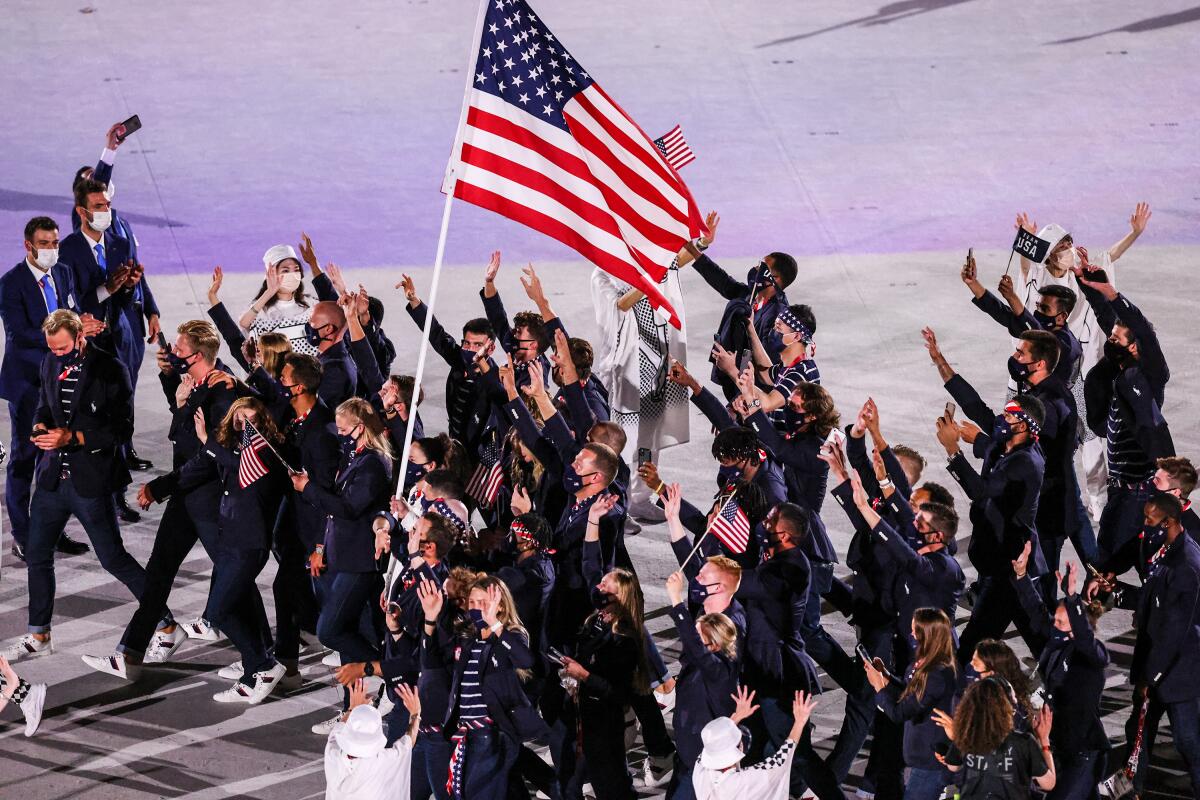 U.S. athletes wave surrounding the flag during the Tokyo Olympics opening ceremony.