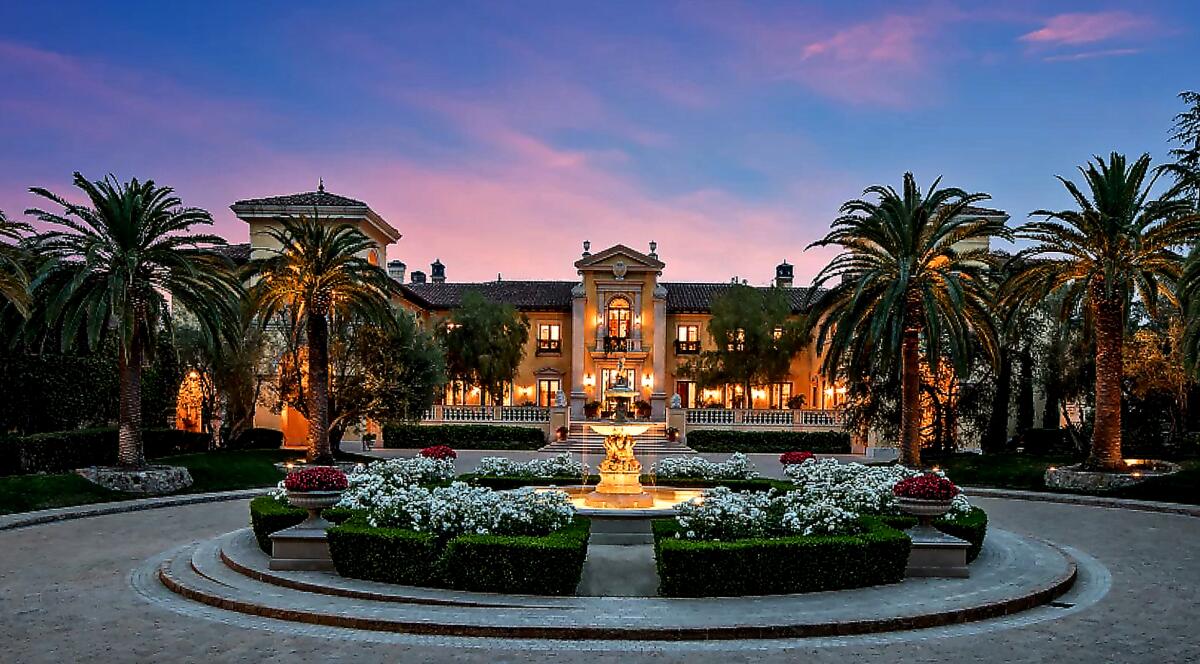 A mansion fronted by a circular drive with a fountain.