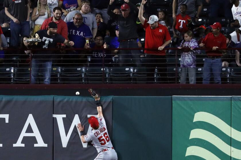 Fans look on as a ball that bounced off the top of Los Angeles Angels right fielder Kole Calhoun's glove falls over the fence for a Texas Rangers' Asdrubal Cabrera two-run home run in the fourth inning of a baseball game in Arlington, Texas, Tuesday, April 16, 2019. (AP Photo/Tony Gutierrez)