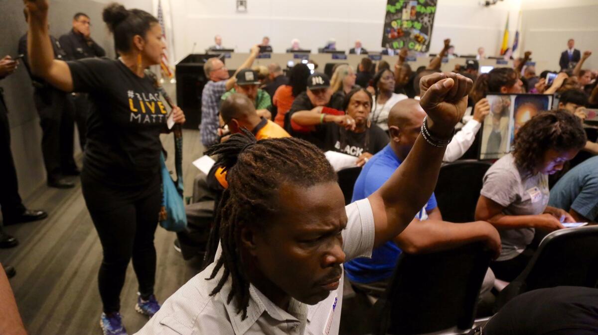 Activists, angered by two fatal shootings by LAPD officers during one October weekend last year, turn their back to LAPD Chief Charlie Beck as he speaks during a Police Commission meeting.