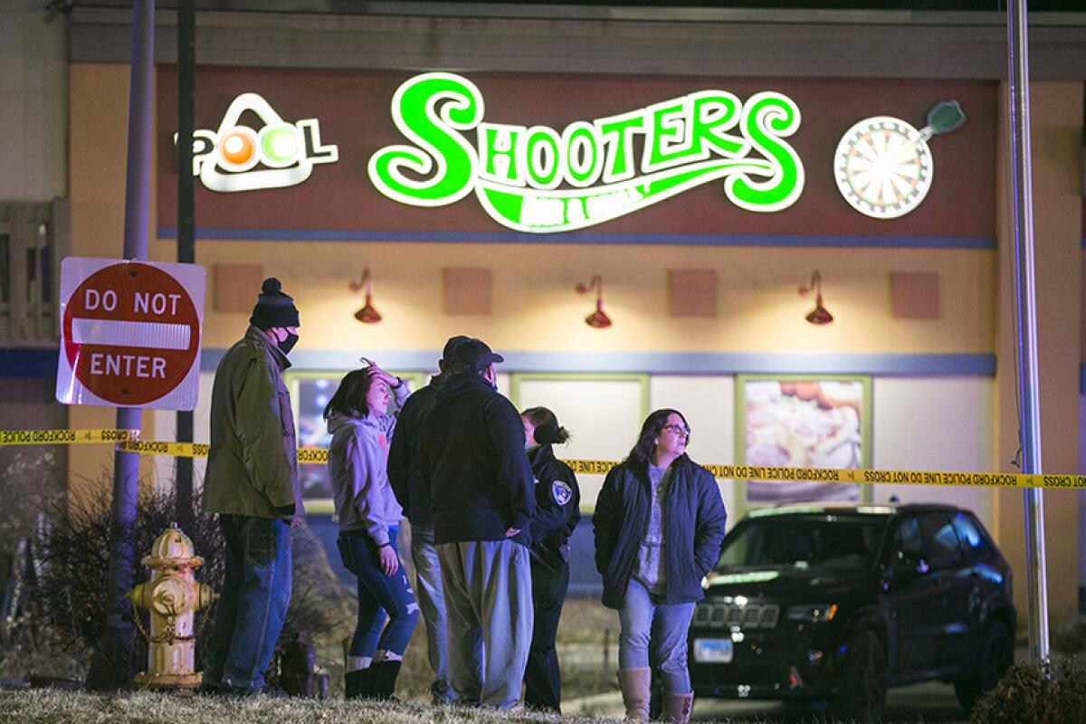 Police question people outside a bowling alley near yellow police tape.
