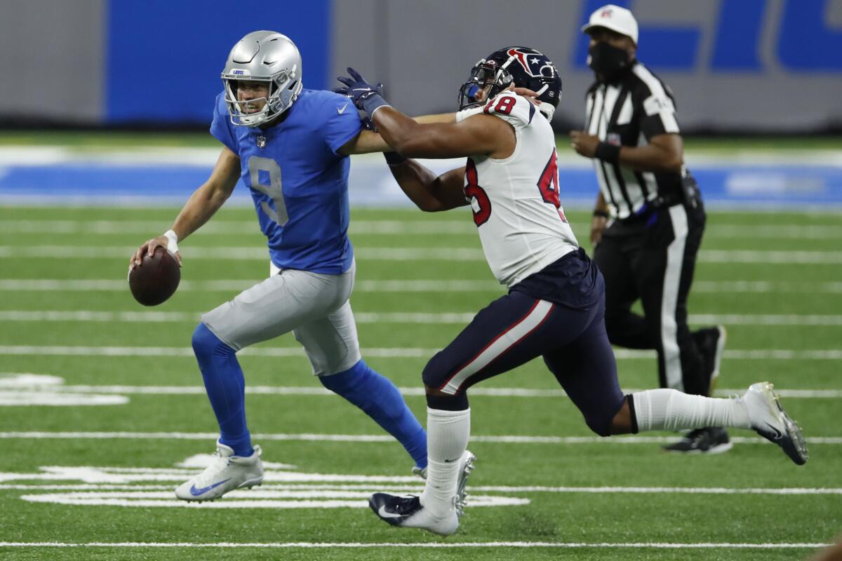 Detroit Lions quarterback Matthew Stafford holds the ball while followed by Houston Texans linebacker Nate Hall
