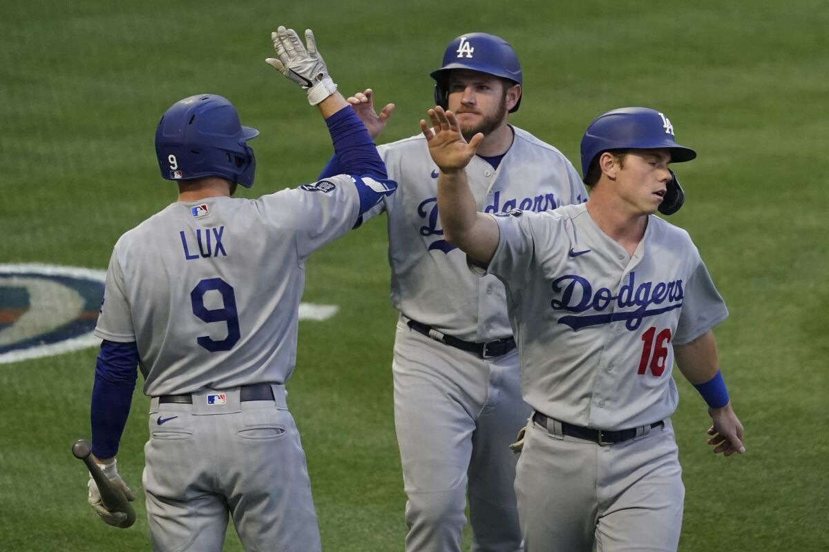 Dodgers teammate Gavin Lux high-fives Max Muncy and Will Smith after they scored off of a line drive by Matt Beaty.