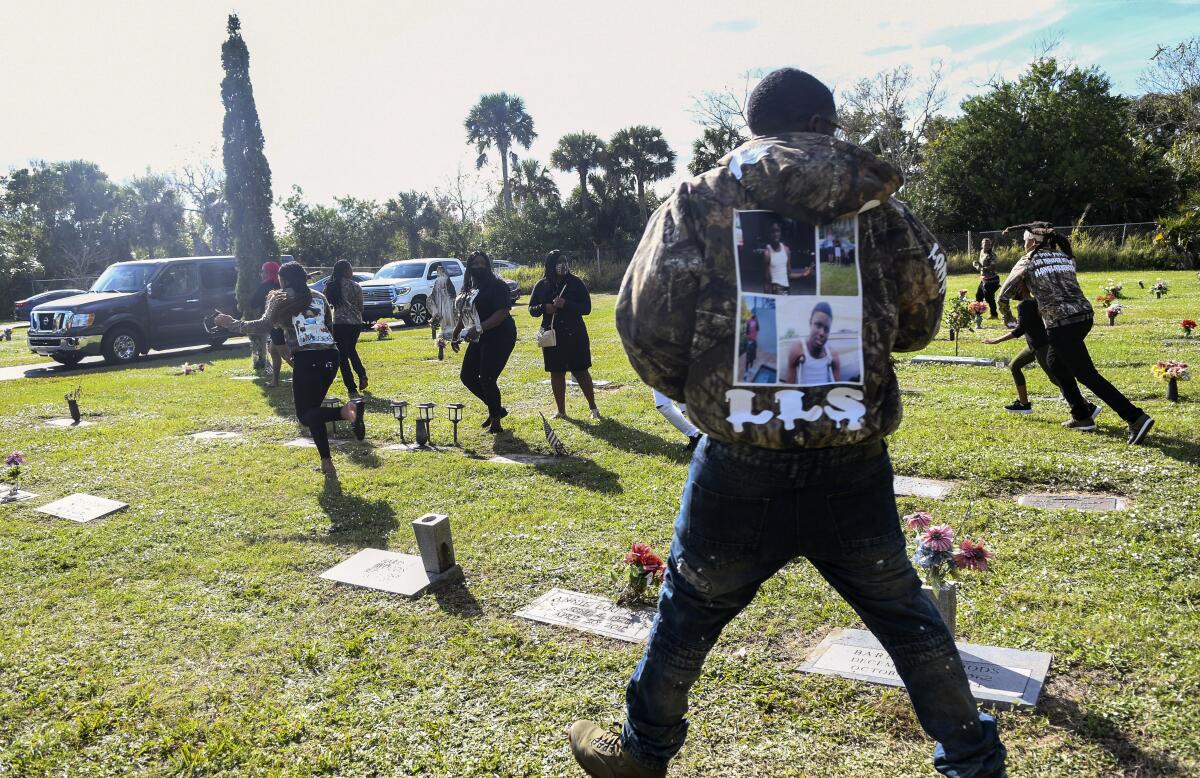 Individuals run through a cemetery after a shot was fired during a burial service