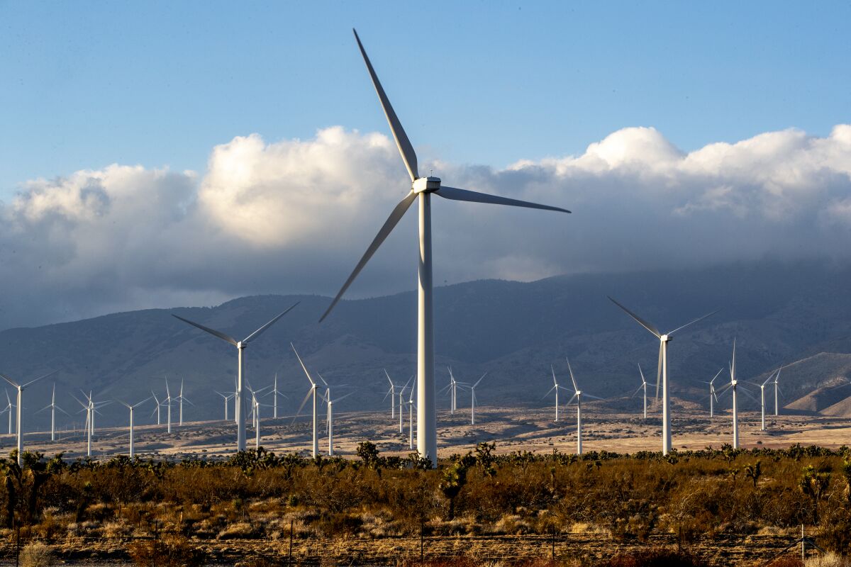 Wind turbines stand in a desert landscape  near the Tehachapi Mountains in Rosamond, Calif.