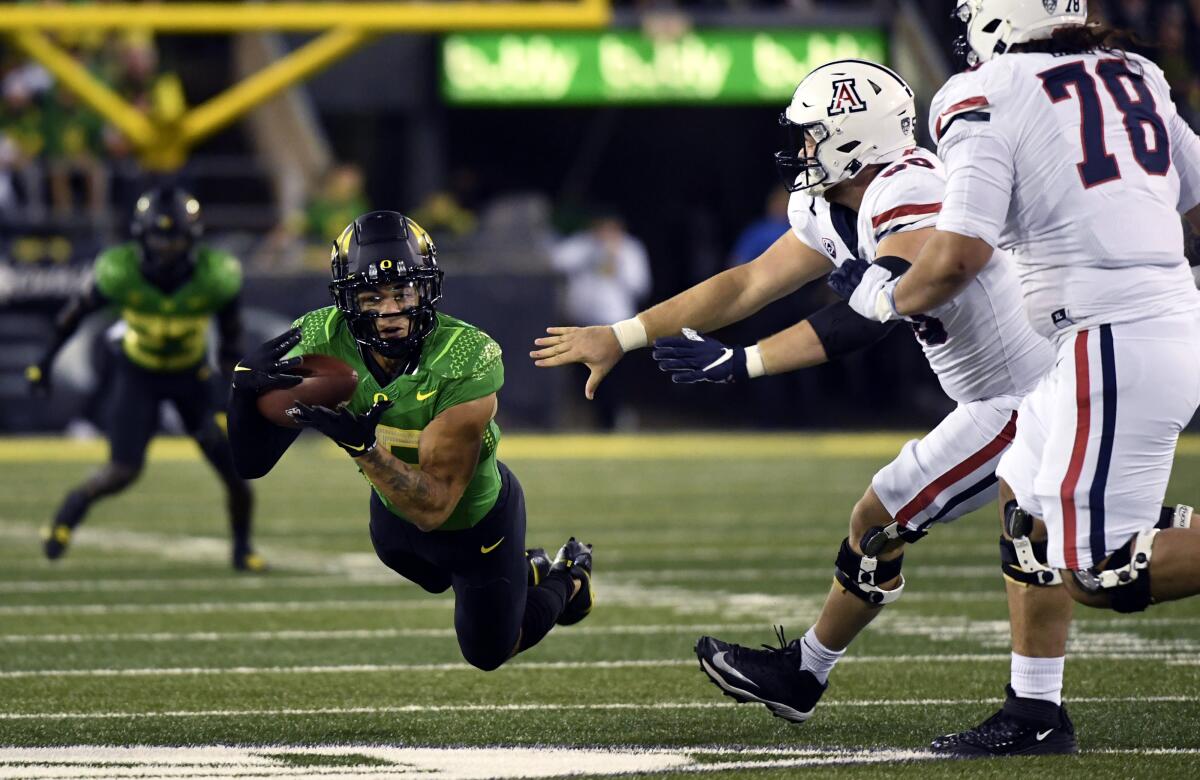Oregon safety Bennett Williams dives to make an interception in front of Arizona's Josh McCauley (50) and Donovan Laie (78).