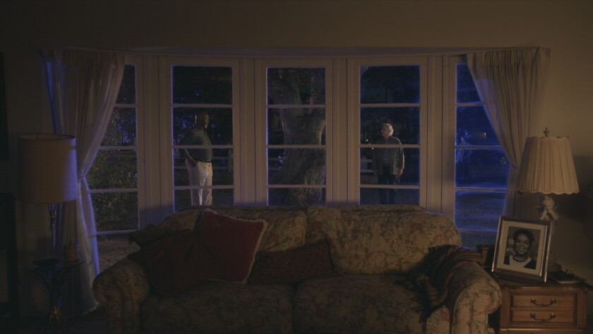 Two men stand outside on the lawn in a scene from "Barry" looking out the living room window.