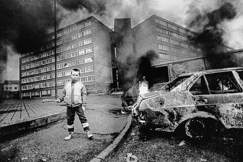 A photograph of a boy and flaming car outside Divis flats featured in the book "Say Nothing: A True Story of Murder and Memory in Northern Ireland." Credit: Doubleday