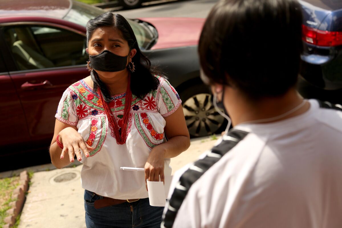 Janet Martinez, left, with CIELO, talks with Luis Gabriel, 17, from Ecatepec de Morelos, Mexico, while giving him a relief check in Los Angeles.