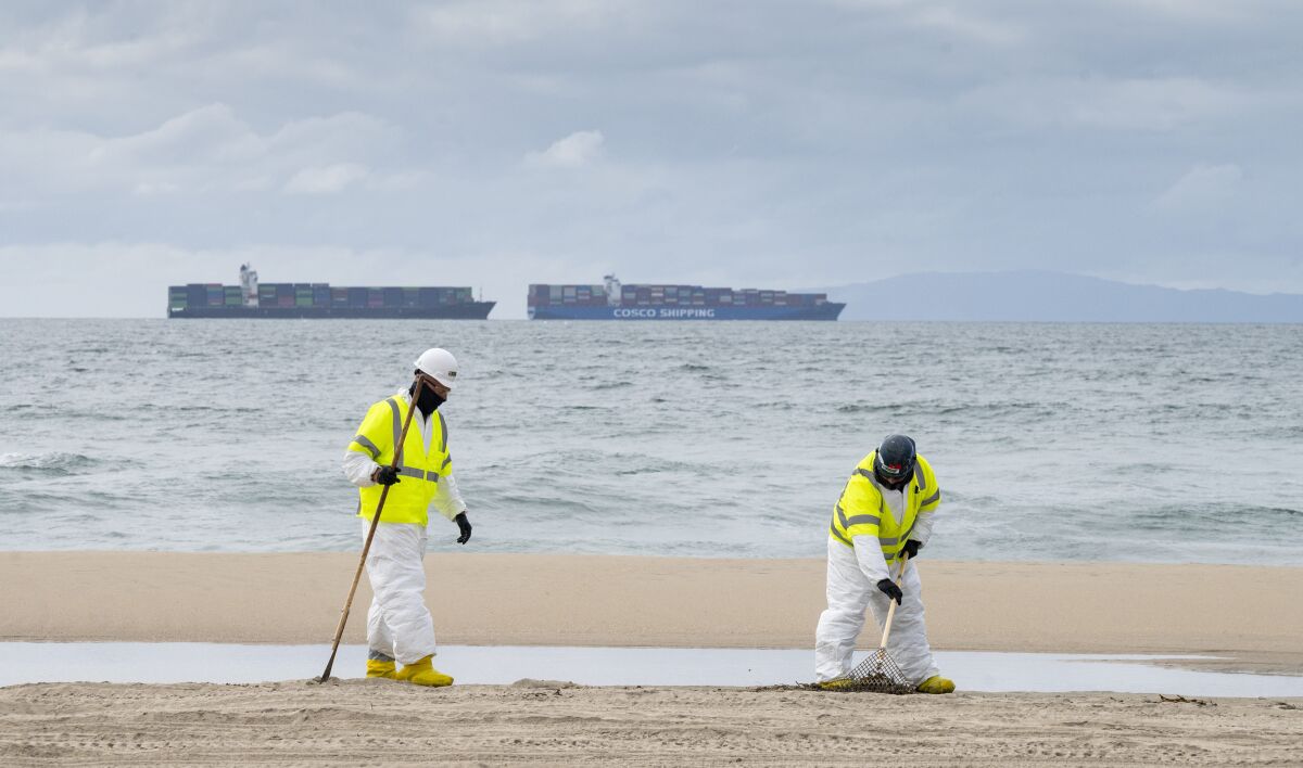 Workers with Patriot Environmental Services clean the sand south of the pier in Huntington Beach, Calif. on Friday, Oct. 8, 2021. Investigators searching for the cause of an undersea oil pipeline break off the Southern California coast have pointed to the possibility that a ship anchor dragged the line across the seabed and cracked it, but two videos released so far provide only tantalizing clues about what might have happened below the ocean surface. (Paul Bersebach/The Orange County Register via AP)
