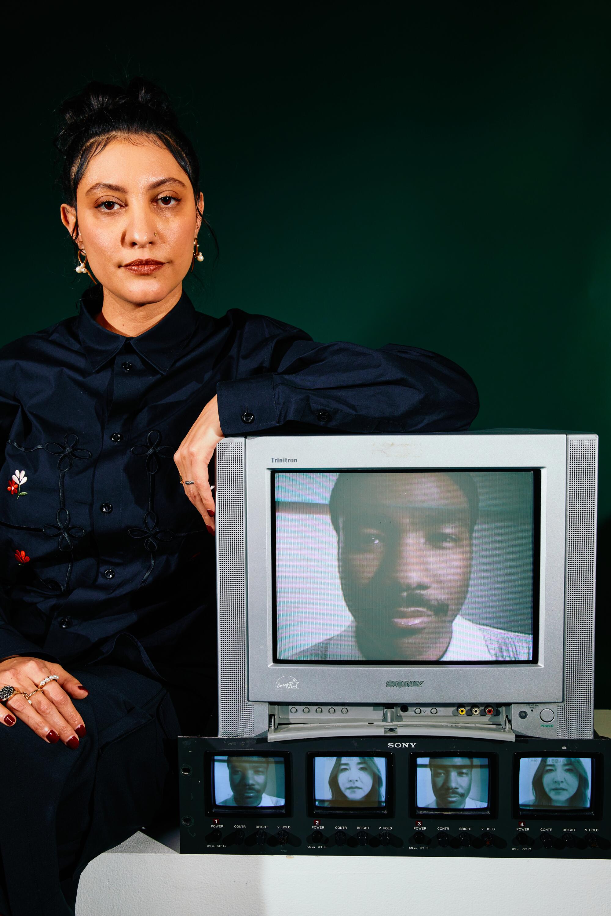 A woman leans her arms against a TV displaying Donald Glover's face.