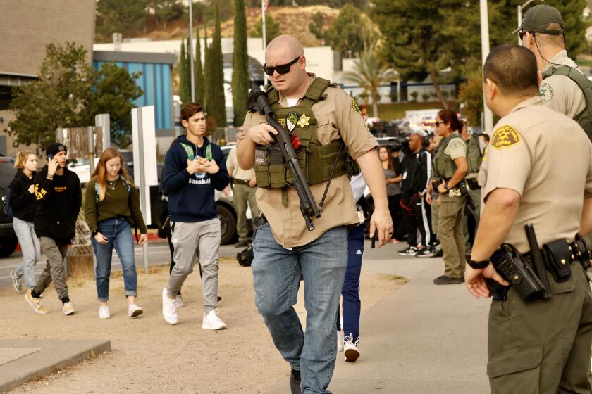 SANTA CLARITA CA NOVEMBER 14, 2019 -- An L.A. County Sheriff's deputy leads students from Saugus High School, where a shooting Thursday morning left 1 dead, at least four others wounded on the Santa Clarita campus, November 14, 2019. (Al Seib / Los Angeles Times)