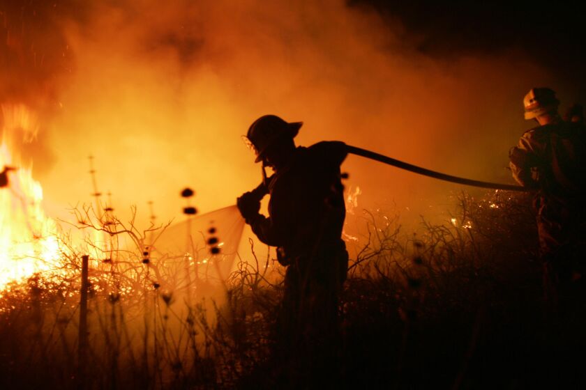 A firefighter hoses flames spread by Santa Ana winds in 2007.