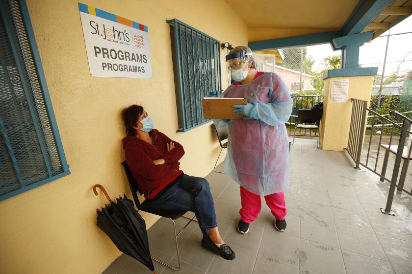 LOS ANGELES, CA - MAY 18: Maria Banderas, left, answers questions from medical assistant Dolores Becerra before entering the room where she will receive the oral swab test for coronavirus during walk-in coronavirus testing at St. John's Well Child and Family Center in South Los Angeles, one of the South and Central LA neighborhoods hit hard by the coronavirus Covid-19. South Central on Monday, May 18, 2020 in Los Angeles, CA. (Al Seib / Los Angeles Times)