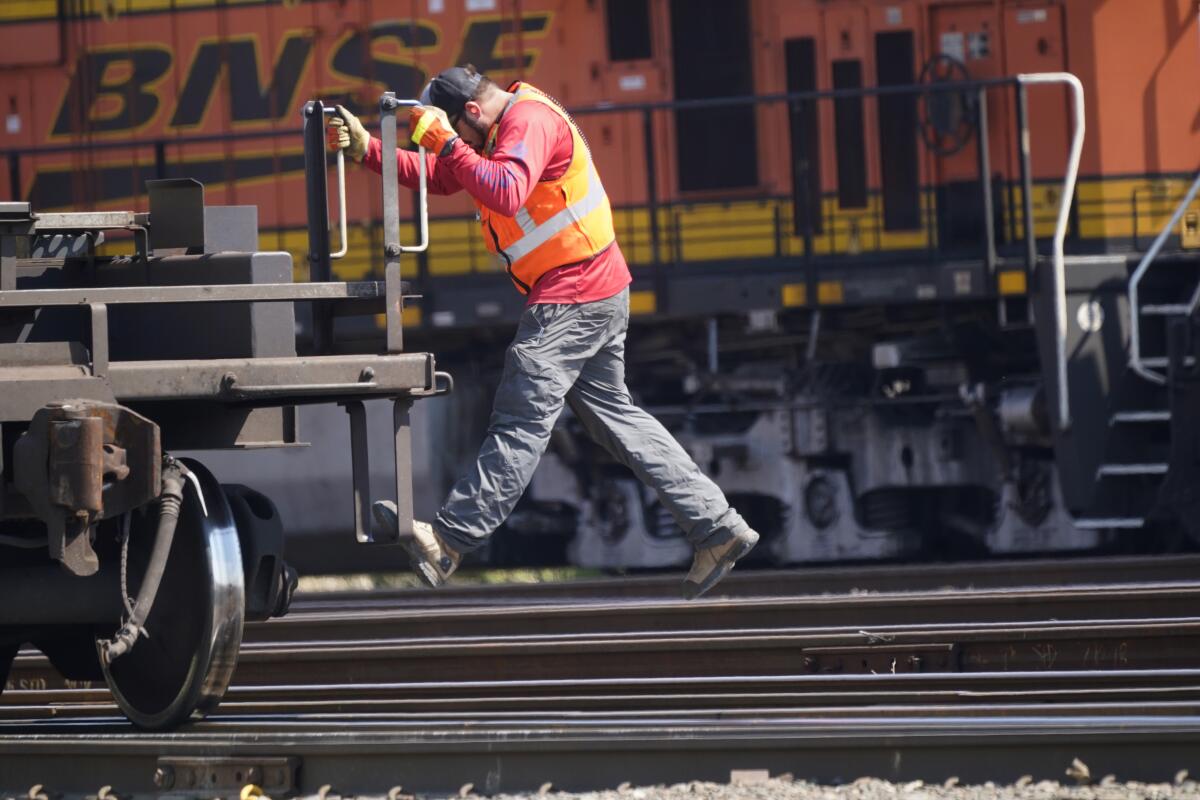 A worker rides a rail car at a BNSF rail crossing in Saginaw, Texas, Wednesday, Sept. 14, 2022. Business and government officials are preparing for a potential nationwide rail strike at the end of this week while talks carry on between the largest U.S. freight railroads and their unions. (AP Photo/LM Otero)