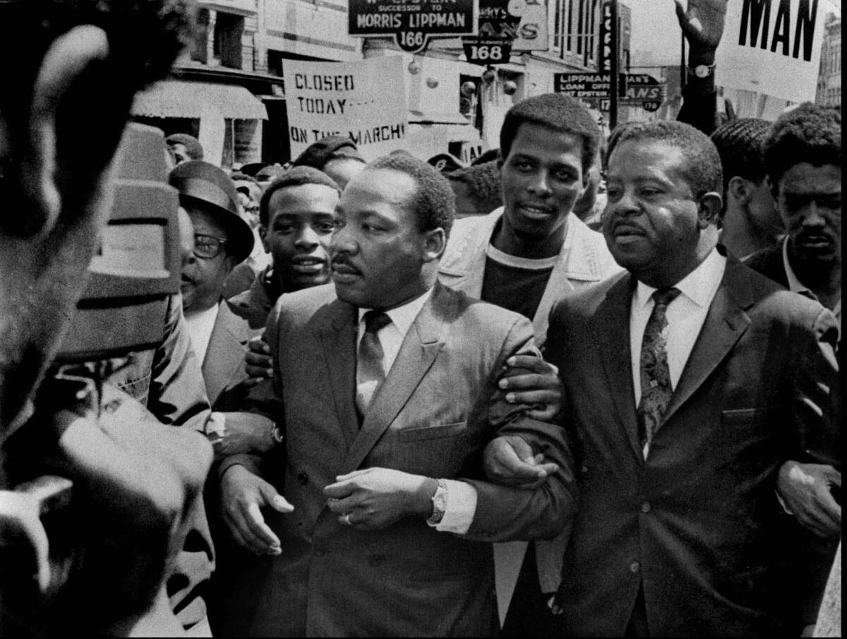 Dr. Martin Luther King Jr. and Rev. Ralph Abernathy, right, lead a march on behalf of striking Memphis sanitation workers on March 28, 1968. The dignity of the march soon gave way to disorder as a group of about 200 youths began breaking windows and looting. King, who agonized over what had happened, was killed within the week.