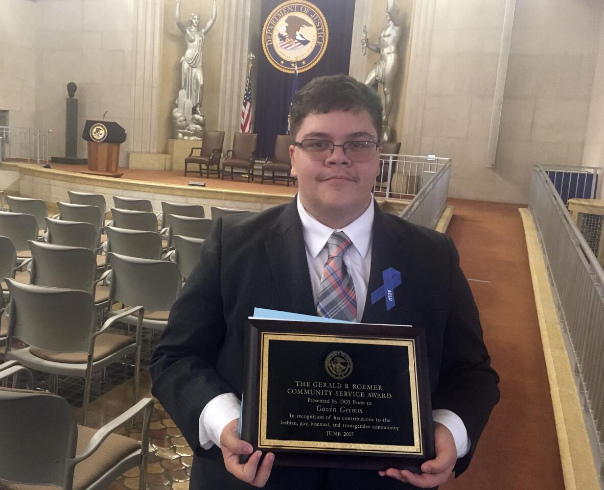 Gavin Grimm stands with his award after being honored at the Justice Department on Wednesday, June 28, 2017, in Washington. The transgender teen who sued to be able to use the boys' bathroom was honored by members of a Justice Department whose leadership undercut his landmark case before it could be heard by the Supreme Court. DOJ Pride, an organization of LGBT Justice Department employees, recognized Grimmâ€™s â€œoutstanding contributions to the LGBT communityâ€ during a ceremony in the buildingâ€™s Great Hall, where department attorneys and employees lined up to hug him and offer congratulations and thanks.(AP Photo/Sadie Gurman)