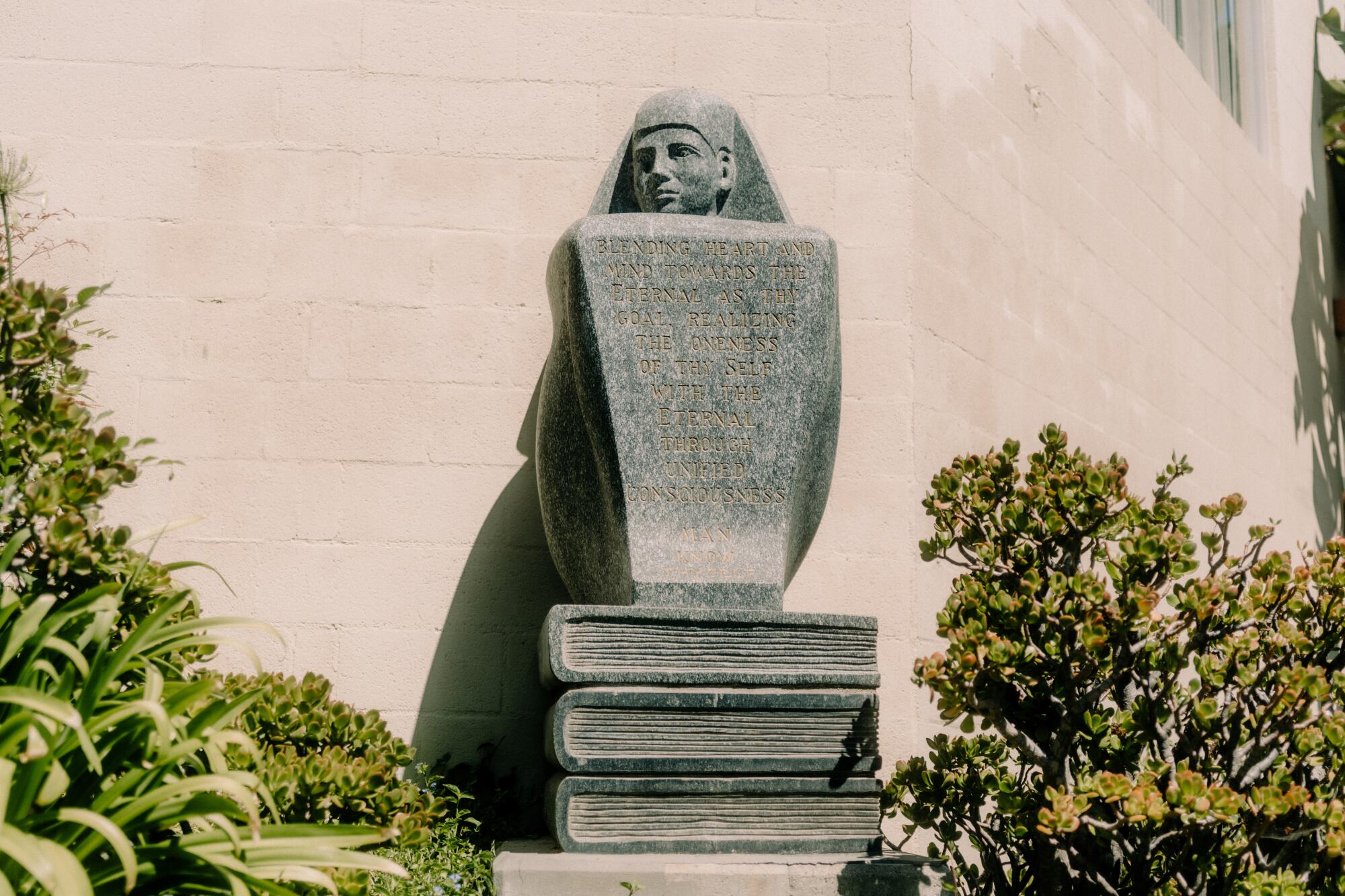 A statue of a head floating above a plaque and three books outside the Philosophical Research Society.