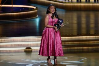 Quinta Brunson accepts her second Emmy Award onstage while wearing a pink, crushed satin gown