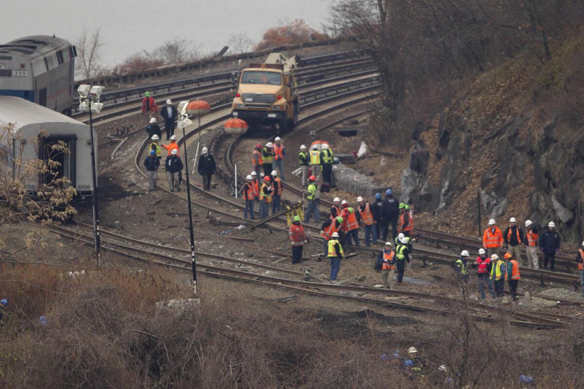 Officials look at the damaged tracks Monday in New York where a train derailed Sunday, killing four people and injuring about 60.