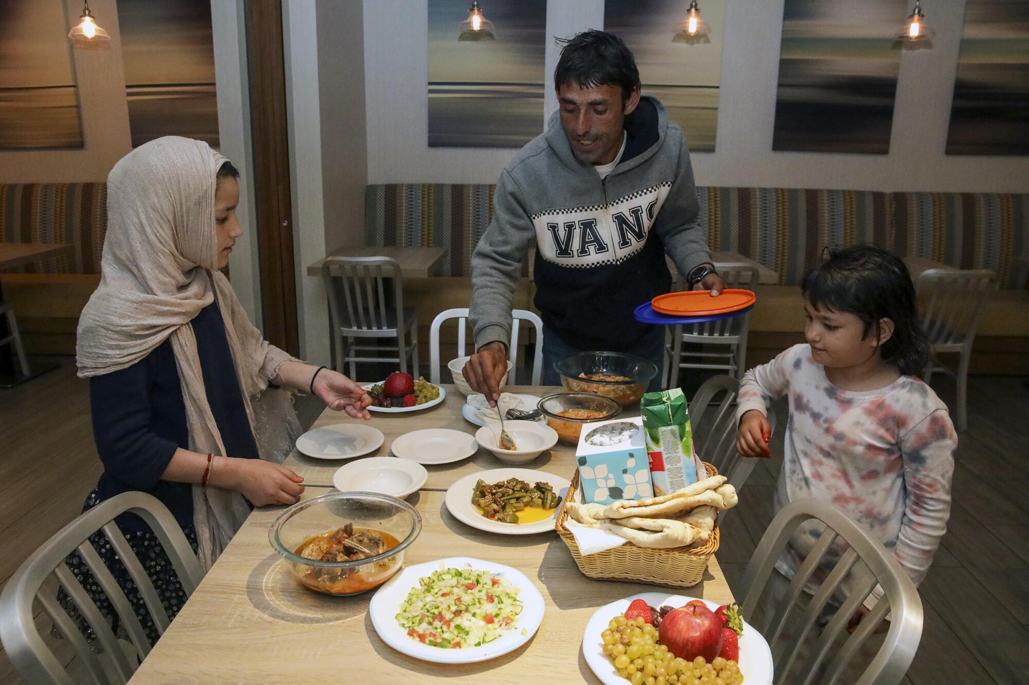 A man and two child get food at a table.