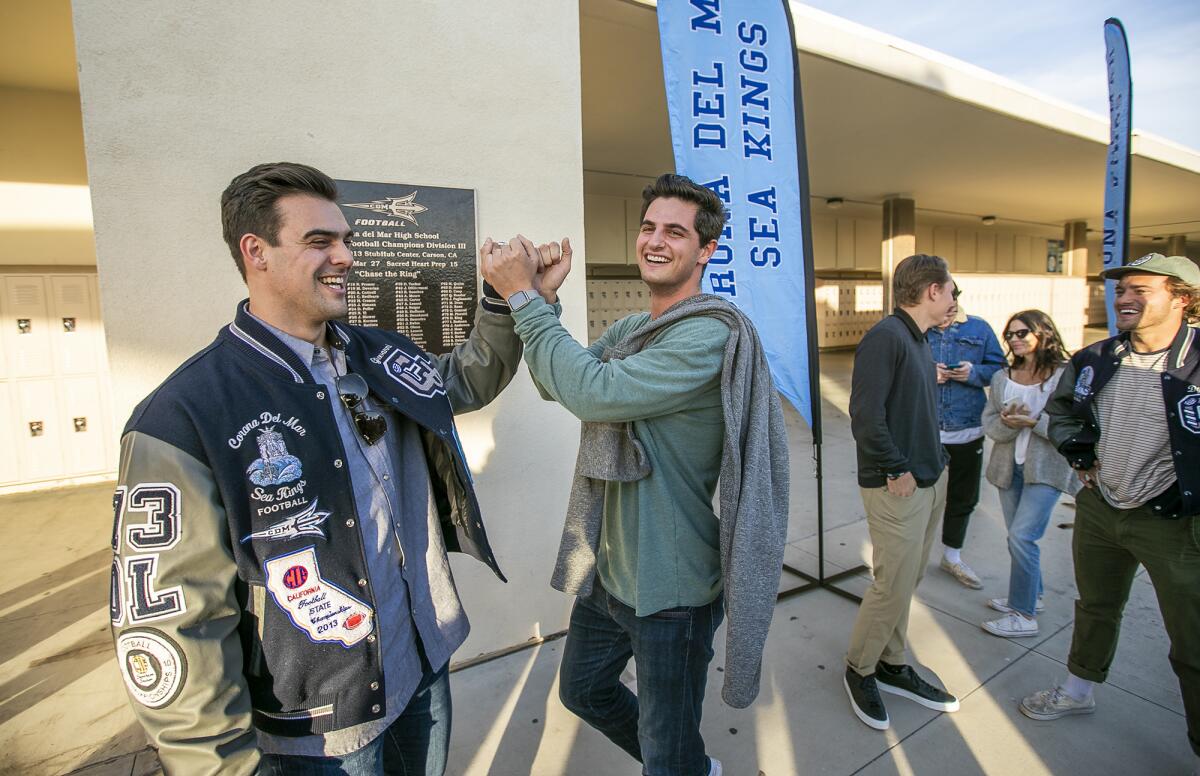 Giovanni Gentosi, left, and Luke Napolitano high-five during the unveiling of a plaque commemorating the 2013 Corona del Mar football team winning the program's first CIF State title.