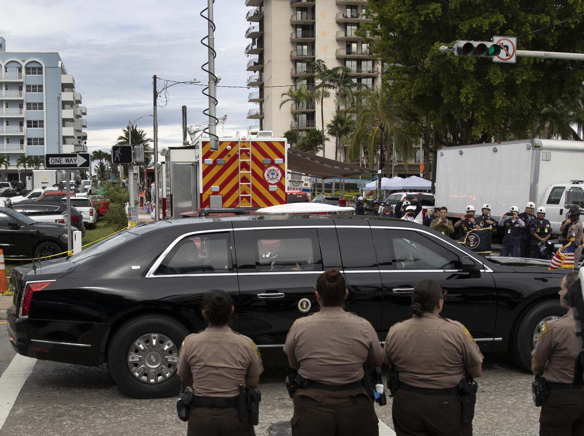 Biden's vehicle passes between lines of law enforcement officers.