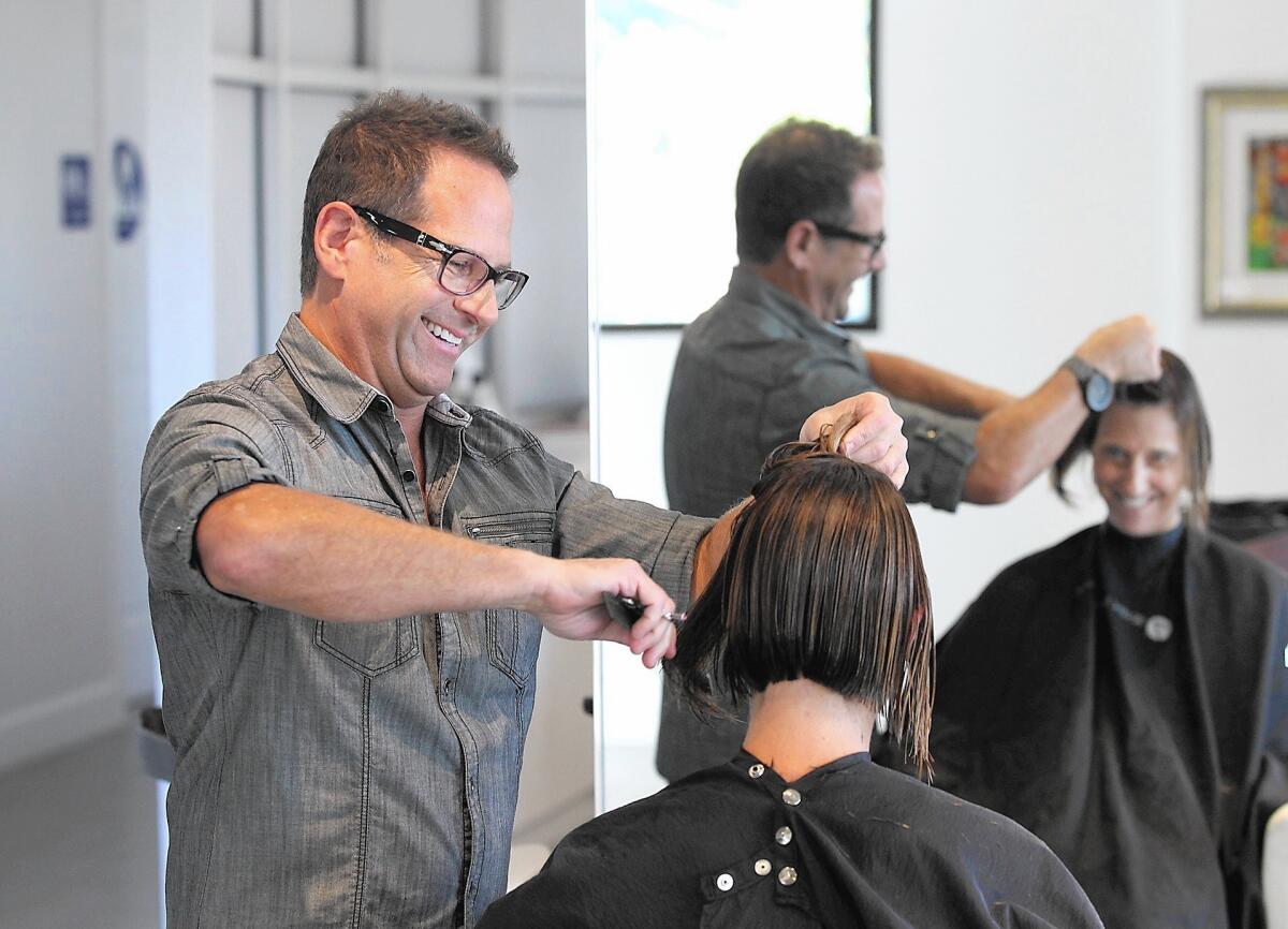 Newport Beach-based hairstylist Dennis Lee shares a story with client Robin Vest at the Armando Joshua Christopher Hair Salon in Newport Beach. Lee recently won the "Making the Cut" competition and was named the top hairstylist in Southern California.