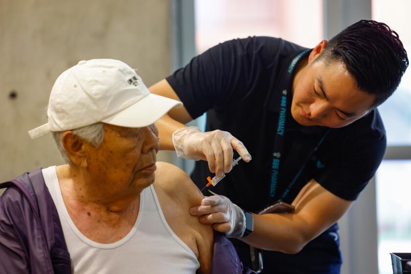 Los Angeles, CA - October 11: Dr.Yang Alex Ou, pharmacist with 986 Pharmacy, gives a covid vaccination to a resident at Stovall Terrace Apartments a senior community on Wednesday, Oct. 11, 2023 in Los Angeles, CA. (Jason Armond / Los Angeles Times)