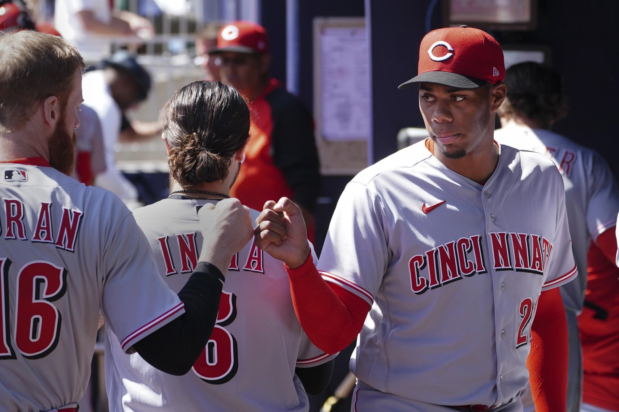 Cincinnati Reds starting pitcher Hunter Greene is greeted by teammates in the dugout.