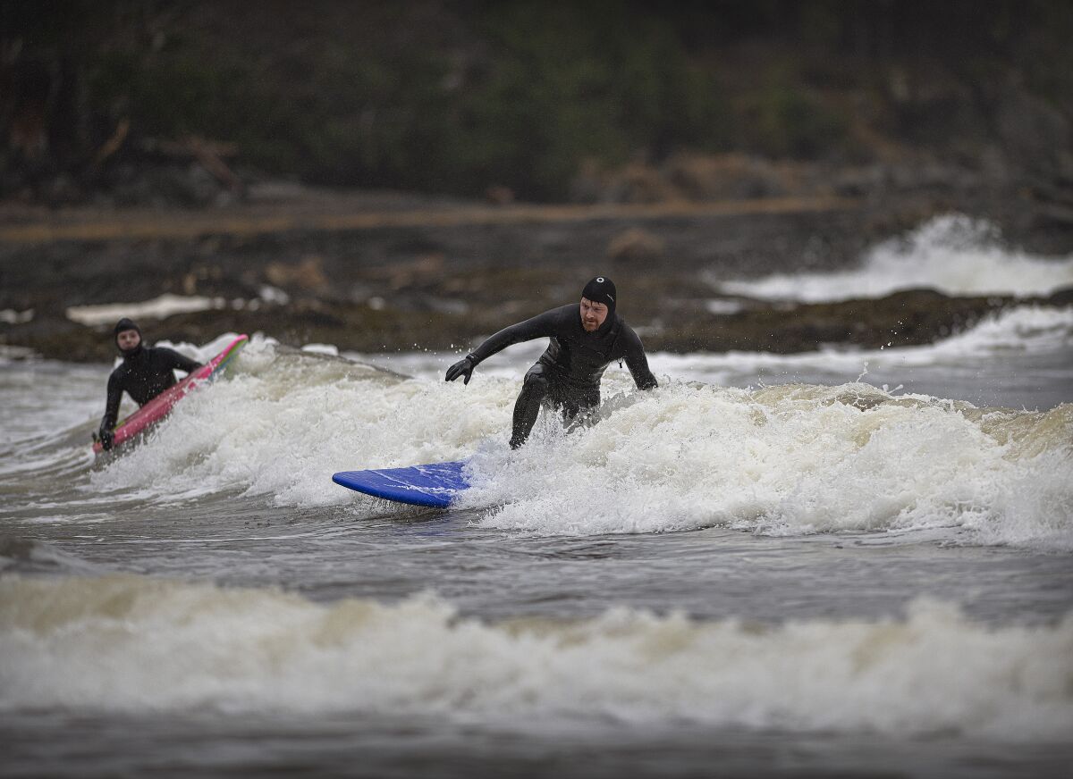 Husband and wife Nick and Jaimie-lee Mitchell surf on Sunday, Dec. 6, 2020, at Rotary Beach in Ketchikan, Alaska. Ongoing storms have provided groups of surfers the opportunity to catch waves this holiday season. (Dustin Safranek/Ketchikan Daily News via AP)