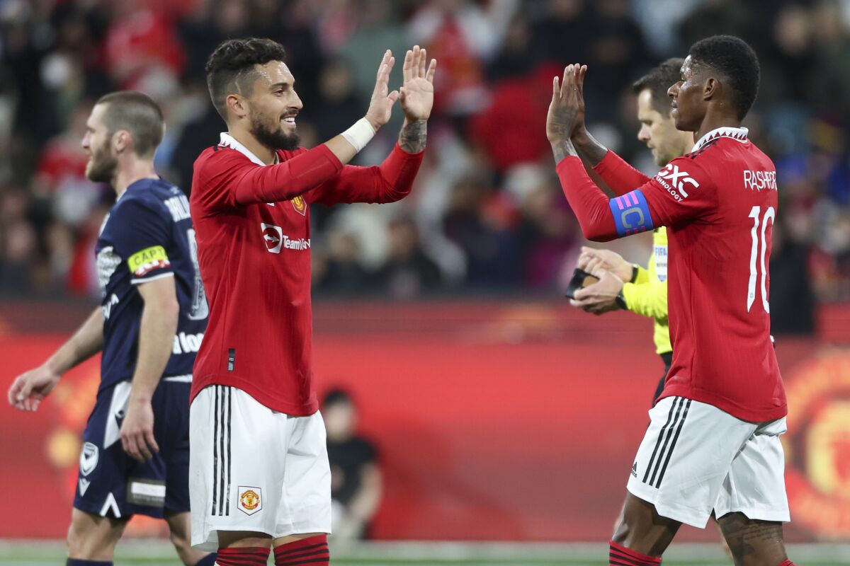 Manchester United's Alex Telles, left, congratulated teammate Marcus Rashford after scoring his team's third goal during the soccer match between Manchester United and Melbourne Victory at the Melbourne Cricket Ground, Australia, Friday, July 15, 2022. (AP Photo/Asanka Brendon Ratnayake)