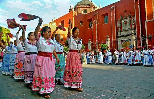 Local women, in colorful embroidered dresses and aprons, celebrate a religious holiday with folk dances.