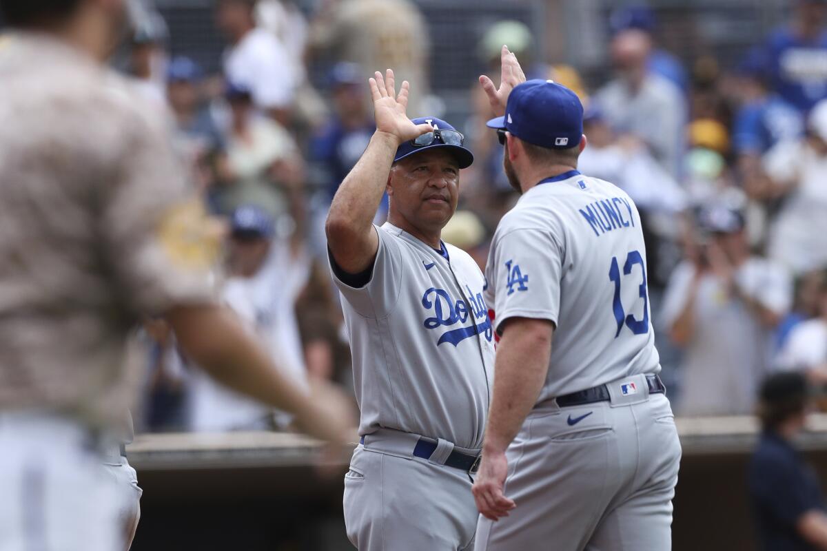 Los Angeles Dodgers manager Dave Roberts, left, congratulates Max Muncy after the team defeated the San Diego Padres in a baseball game, Sunday, Sept. 11, 2022, in San Diego. (AP Photo/Derrick Tuskan)