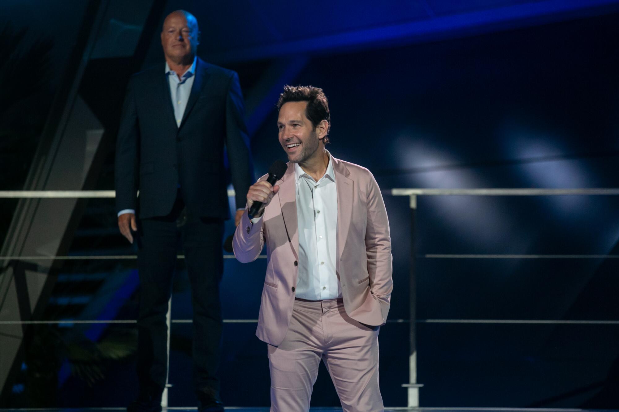 Paul Rudd smiles on stage and speaks into a microphone.