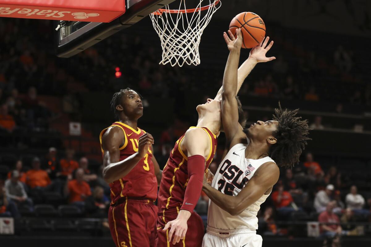 USC's Vince Iwuchukwu, left, and Drew Peterson, middle, reach for a rebound alongside Oregon State's Glenn Taylor Jr.