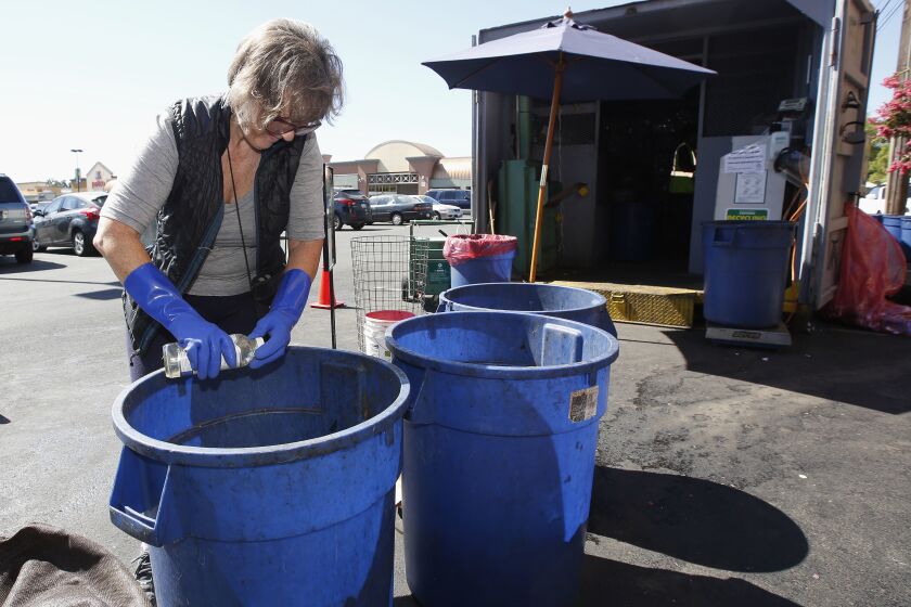 FILE - In this Tuesday, July 5, 2016, file photo, Claudette Cole places a plastic bottle into a plastic container for recycling at a recycling center in Sacramento, Calif. Californians will have a better idea of what's headed for landfills instead of recycling centers under one of several related bills that Gov. Gavin Newsom signed into law Tuesday, Oct. 5, 2021. It sets the nation's strictest standards for which items can display the “chasing arrows” recycling symbol, advocates say. (AP Photo/Rich Pedroncelli, File)