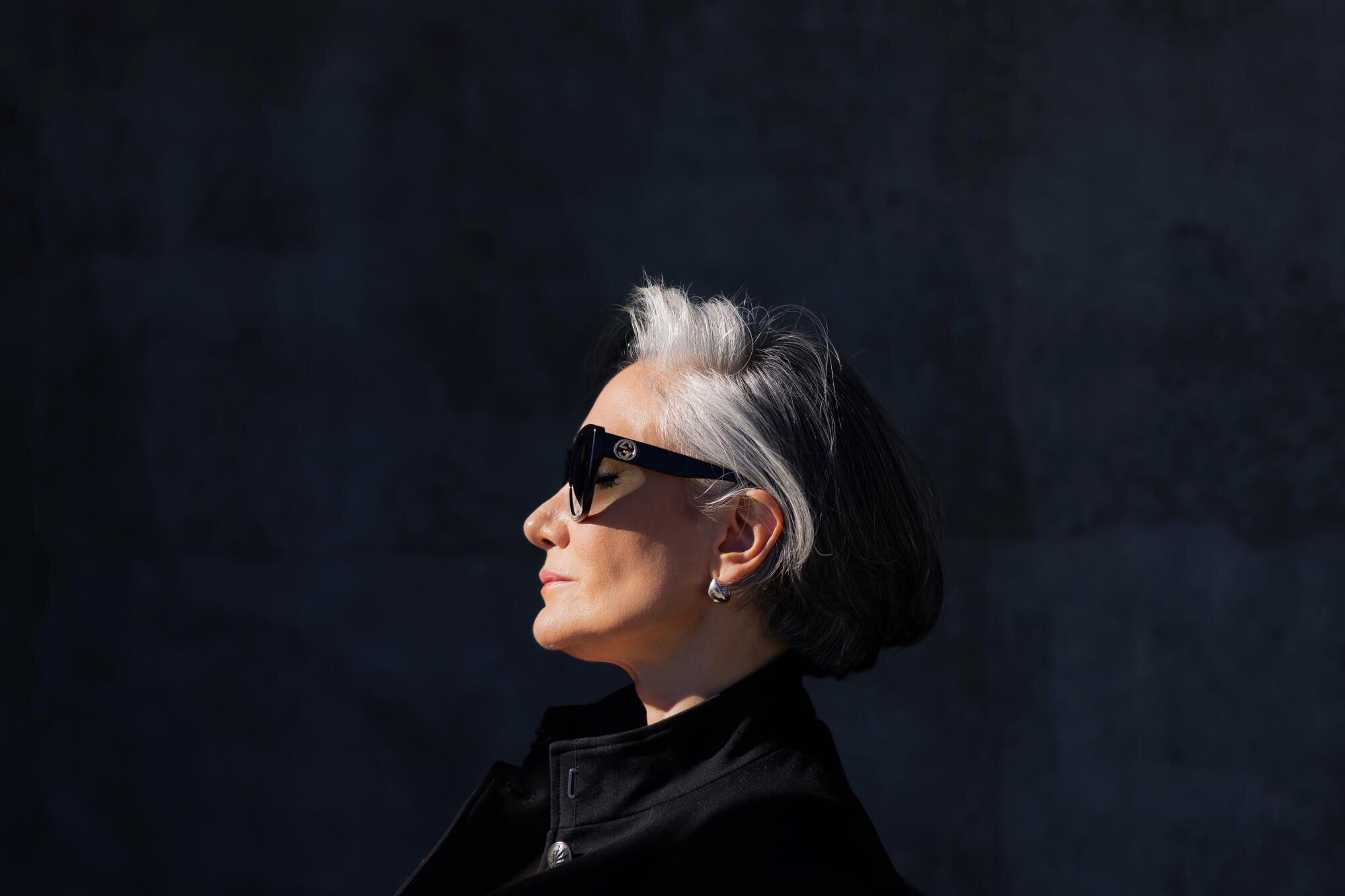 A profile of a woman with her eyes closed and face toward the sun with sunglasses on.