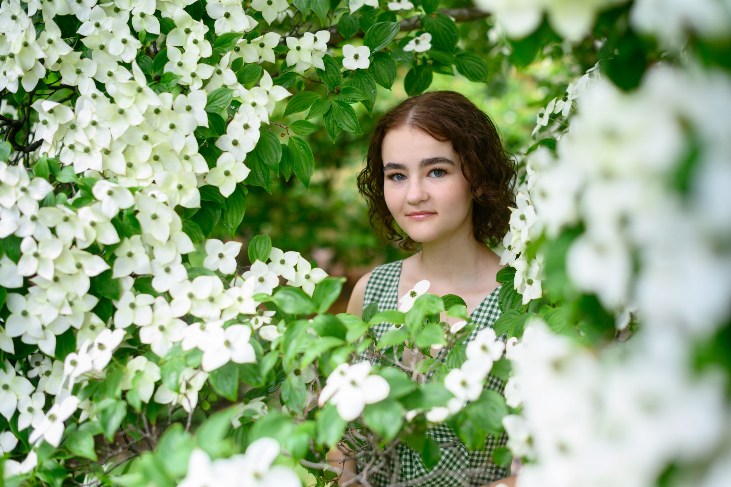 Young actress Millicent Simmonds peers through an opening in a flowering vine.