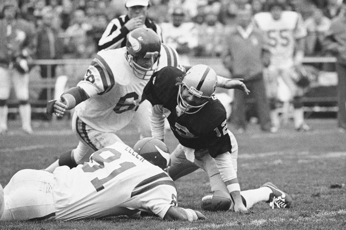 FILE - Oakland Raiders quarterback Ken Stabler (12) grimaces in pain as he recovers a fumble and goes down with twisted knee as Minnesota Vikings' Doug Sutherland (69) and Carl Eller (81) close in during the second quarter of an NFL football game in Oakland, Calif., Dec. 11, 1977. Sutherland, a member of the Purple People Eaters, has died. He was 73. The team released a statement Tuesday, April 5, 2022, without providing a cause. (AP Photo/Sal Veder, File)