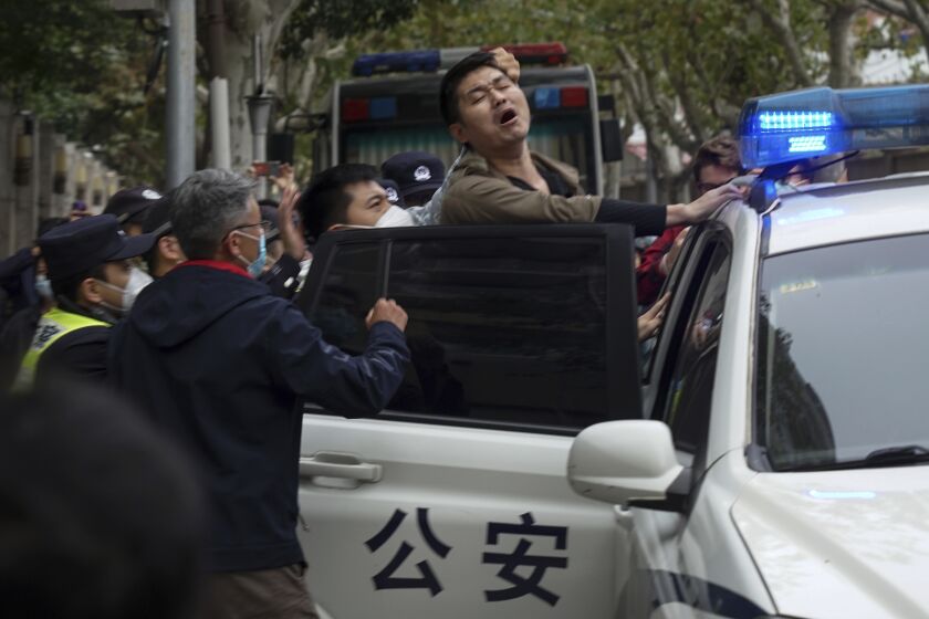 En esta fotografía tomada el domingo 27 de noviembre de 2022, un manifestante es arrestado por policías durante una protesta en una calle de Shanghai, China. (AP Foto)