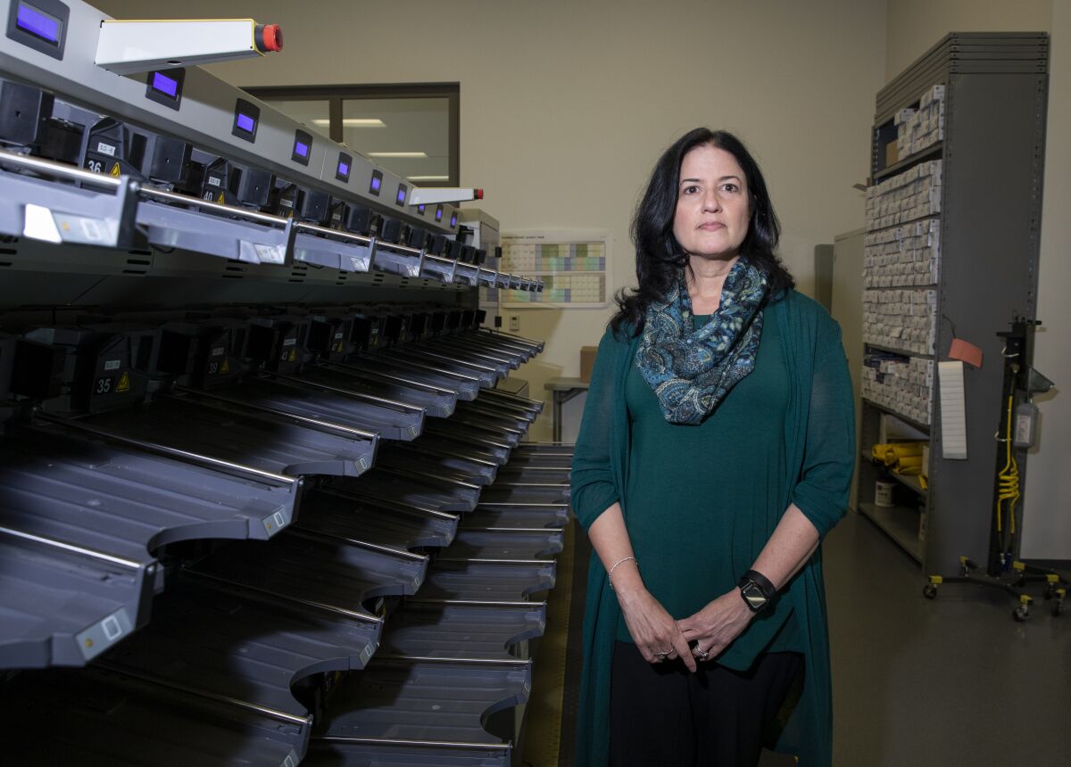  Cynthia L. Paes, San Diego County's interim Registrar of Voters, stands by a sorting machine 