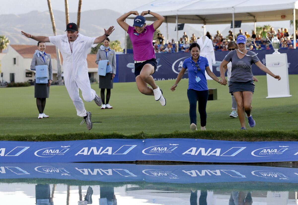 FILE - Lydia Ko, of New Zealand, in pink, forms a heart as she jumps into Champions Lake, or "Poppie's Pond," alongside her caddie, Jason Hamilton, left, after winning the LPGA Tour ANA Inspiration golf tournament at Mission Hills Country Club in Rancho Mirage, Calif., in this Sunday, April 3, 2016, file photo. The longtime major is leaving for the Houston area in 2023 under a new sponsorship with Chevron. (AP Photo/Gregory Bull, File)