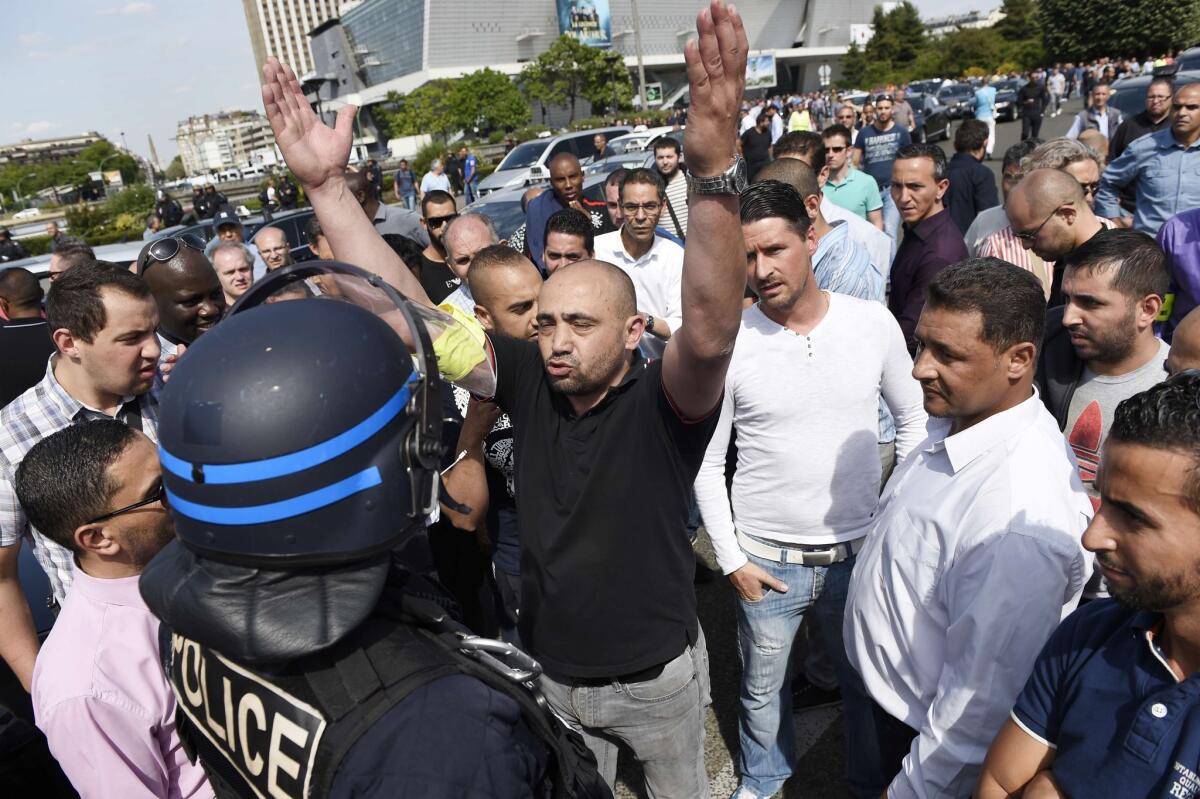 A taxi driver argues with a riot police officer standing guard during a demonstration at the Porte Maillot traffic roundabout on June 25 in Paris.